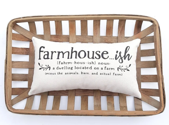 Farmhouse..ish definition pillow sitting inside a woven basket 