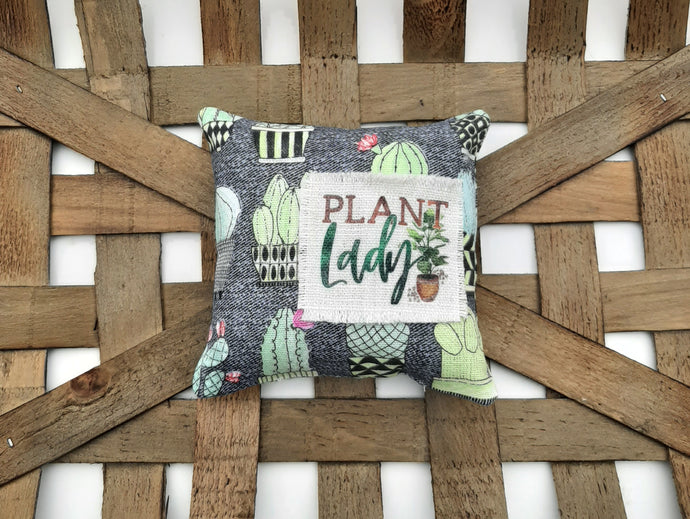 plant lady mini pillow, sitting inside a woven basket 