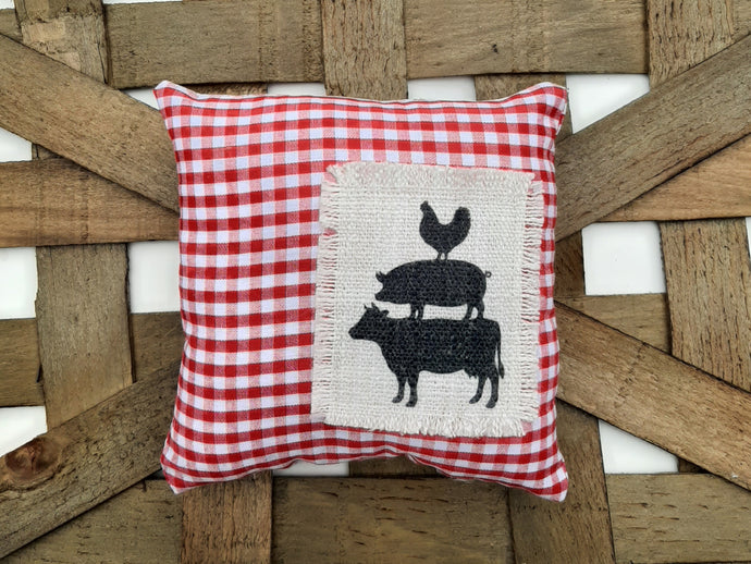 Cow, Pig, Chicken Red and White Gingham Mini Pillow laying a woven basket background