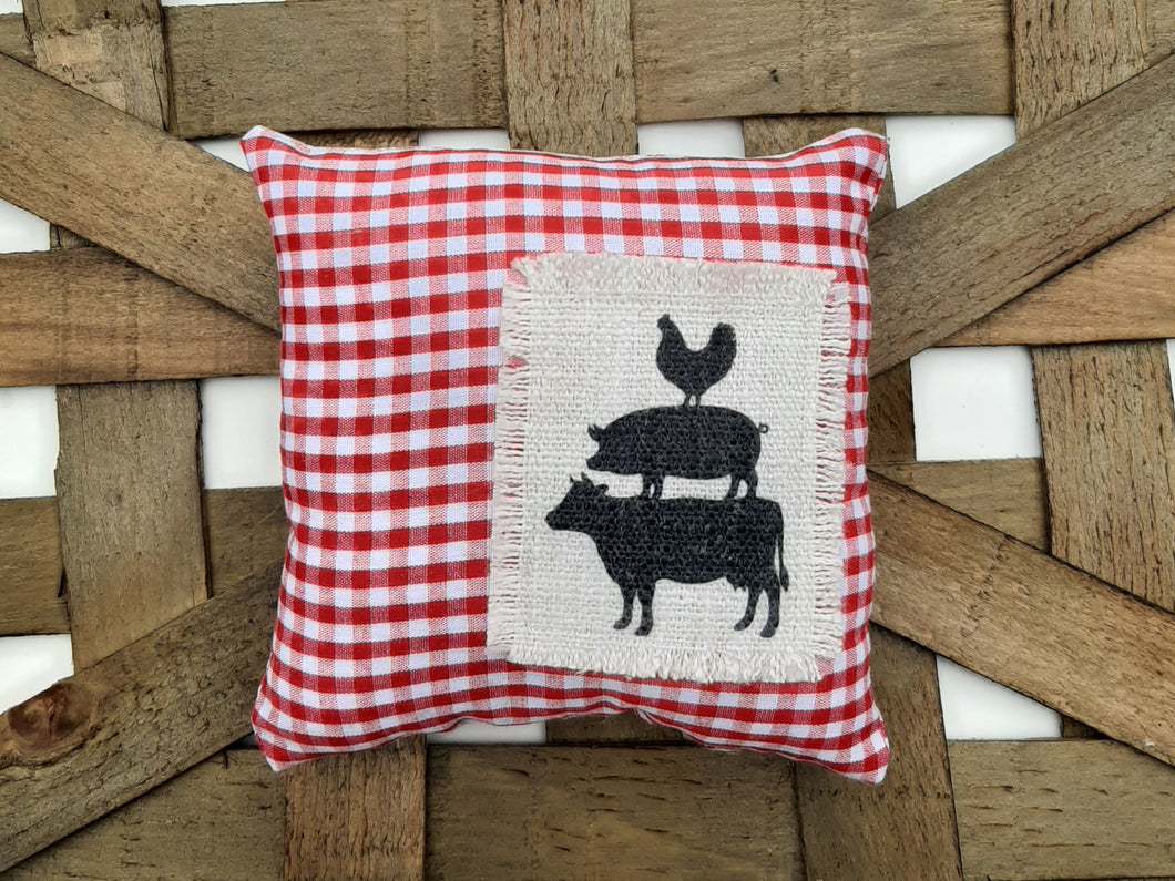 Cow, Pig, Chicken Red and White Gingham Mini Pillow laying a woven basket background