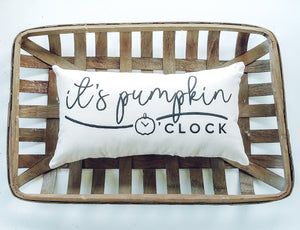 t's Pumpkin Oclock Autumn Lumbar Pillow sitting inside a woven basket