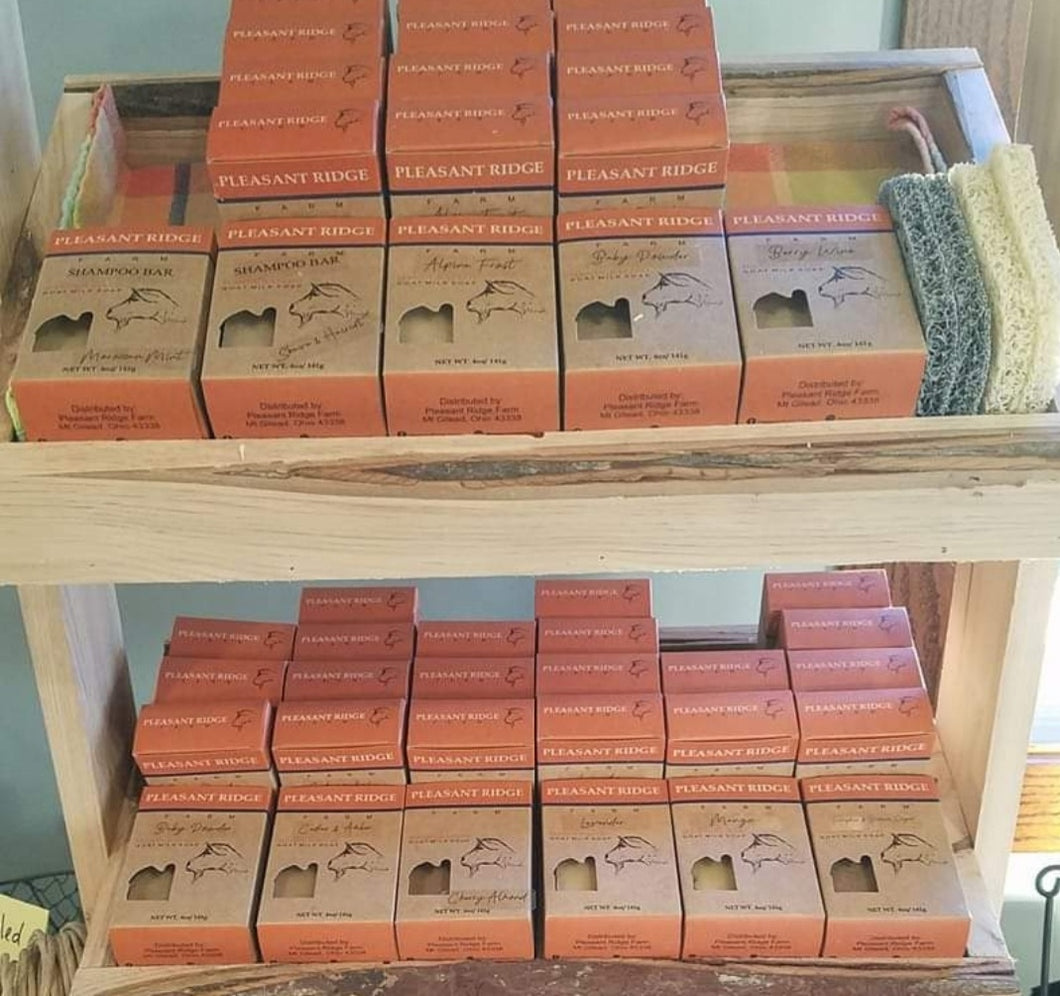 packaged goat milk soap displayed on wooden shelving 