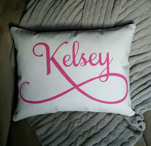 personalized name pillow with pink font laying on a blanket
