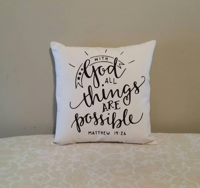 Pillow that reads With God all things are possible | Matthew 19:26, leaning against a tan wall
