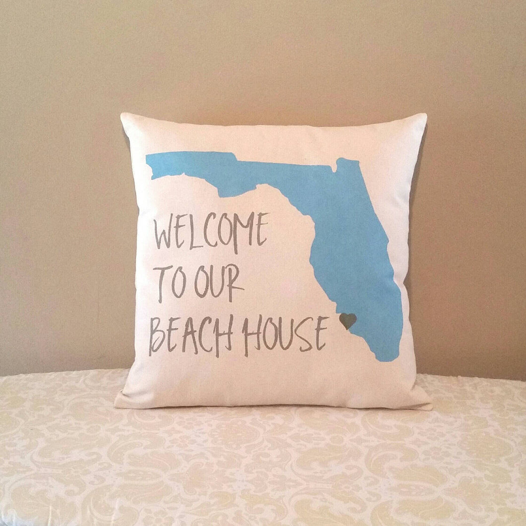welcome to our beach house customizable pillow leaning against a tan wall 