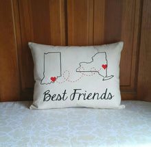 custom state to state long distance best friends pillow, with hearts on city location, leaning against a wooden wall