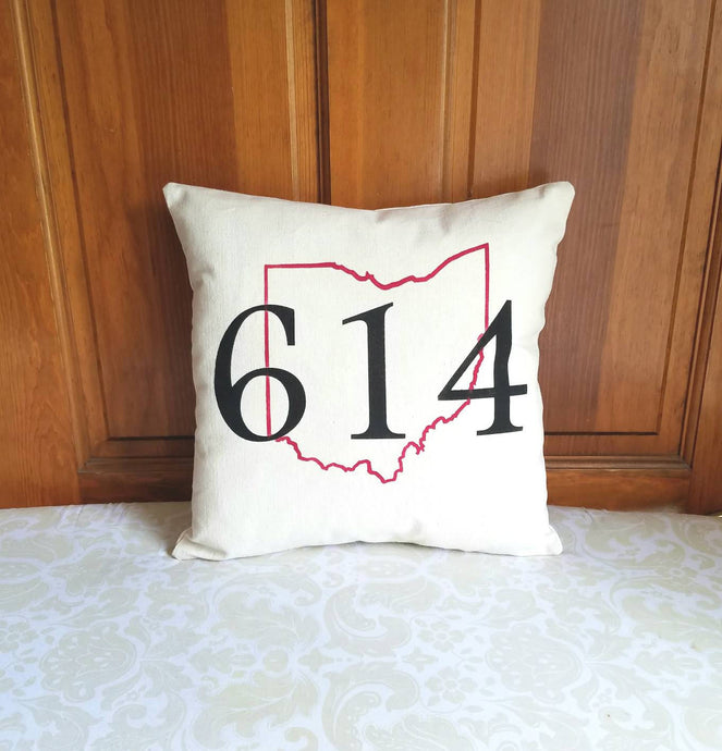Customized area code and state pillow leaning against a wooden door 