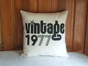 Pillow that says Vintage along with custom birth year, leaning against a wooden door