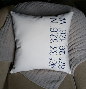 custom GPS coordinates canvas pillow sitting in a cozy chair