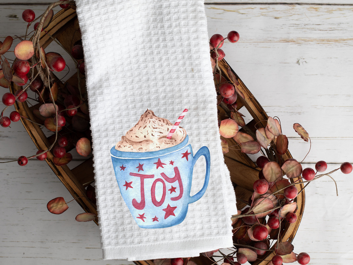 Hot Chocolate Bar Tea Towel with a Watercolor Joy Mug pictured on it, laying across a woven basket with berries 