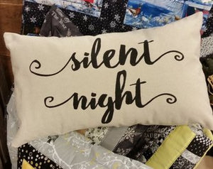 Silent Night Christmas pillow laying on a printed background